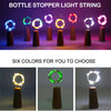 A display of six colored bottle stopper light strings on dark pedestals.