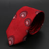 Corbata roja de jacquard con patrón circular repetitivo, doblada sobre fondo oscuro.
