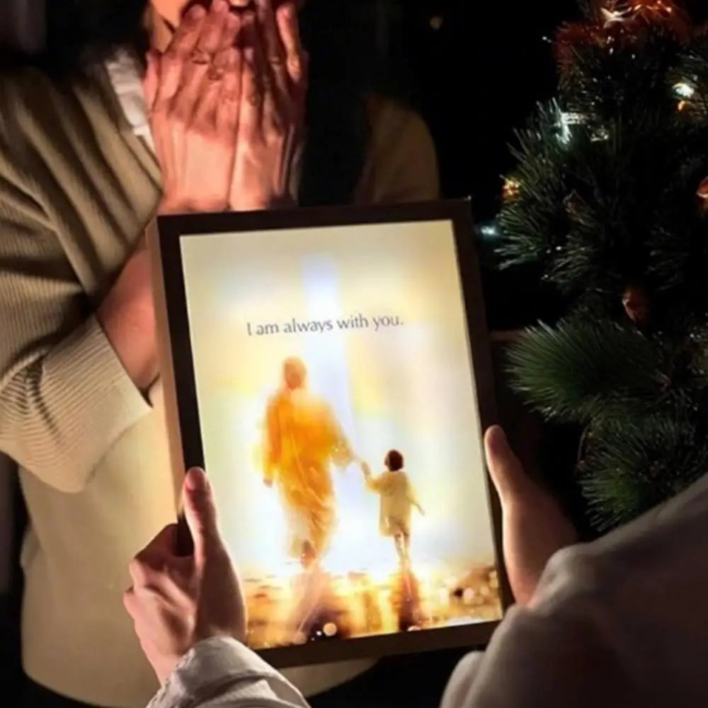En person holder en trævæglampe med silhuet af Jesus og et barn.