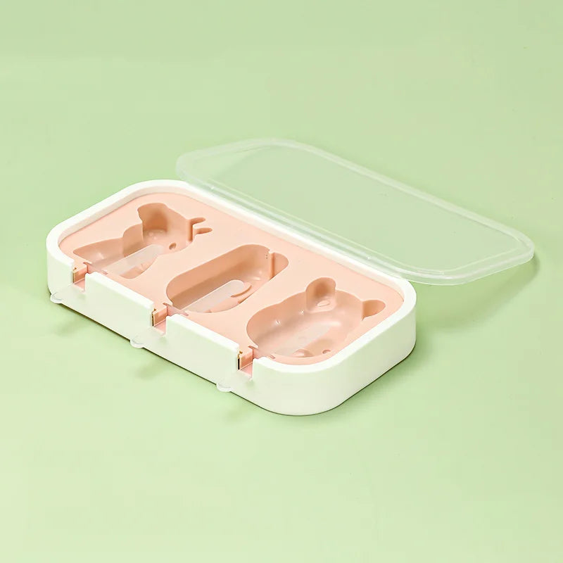 A white silicone mold container with a clear lid holds three pink popsicle shapes for kids.
