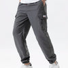 A man wearing gray cargo joggers and white sneakers, showing the fit of the pants.