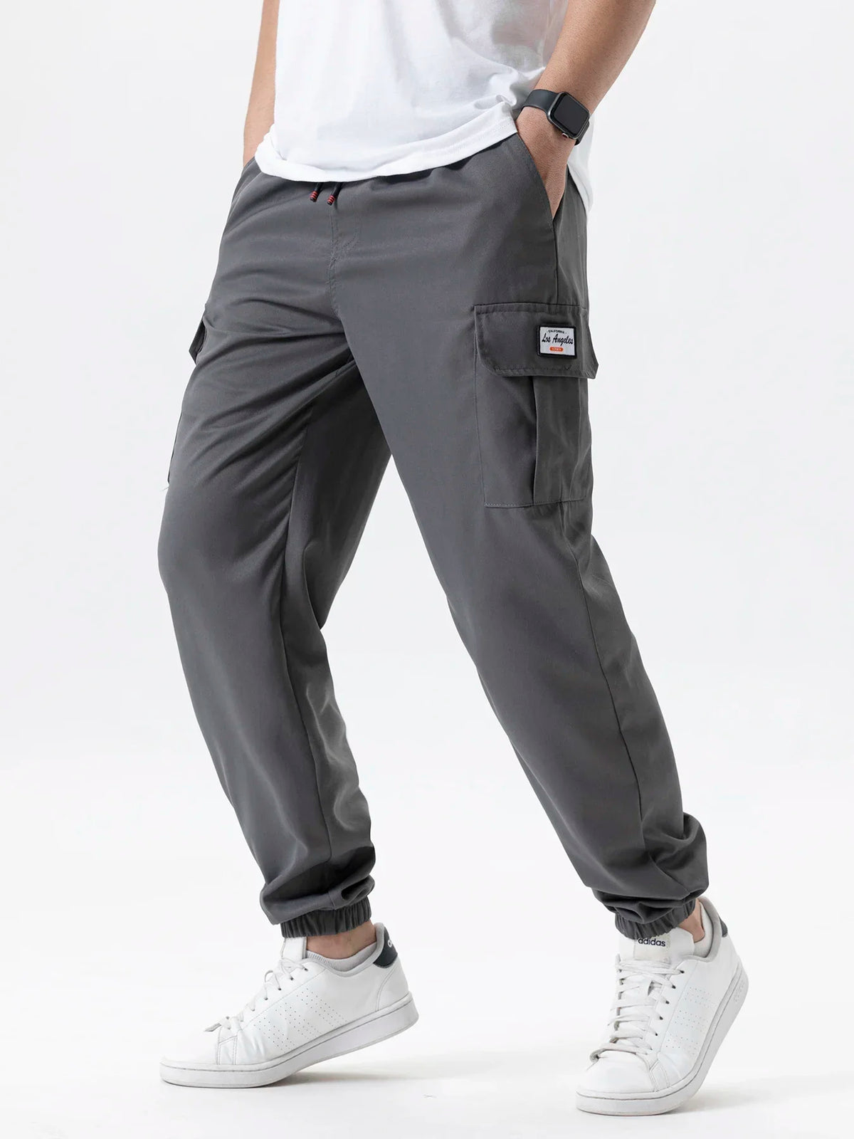 A man wearing gray cargo joggers and white sneakers, showing the fit of the pants.