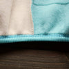 A close-up of a light beige and teal fleece pajama set with ribbed trim on the neckline.