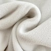 A close-up of a white fleece coat fabric folded and draped.