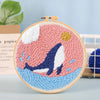 Kit de bordado con aguja mágica con diseño acuarela rosa y azul y silueta oscura de una ballena.