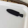A black matte resin side hair clip is shown resting on a white tray.