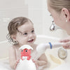 A baby is playing with a white duck and penguin bath toy that sprays water in a bathtub.