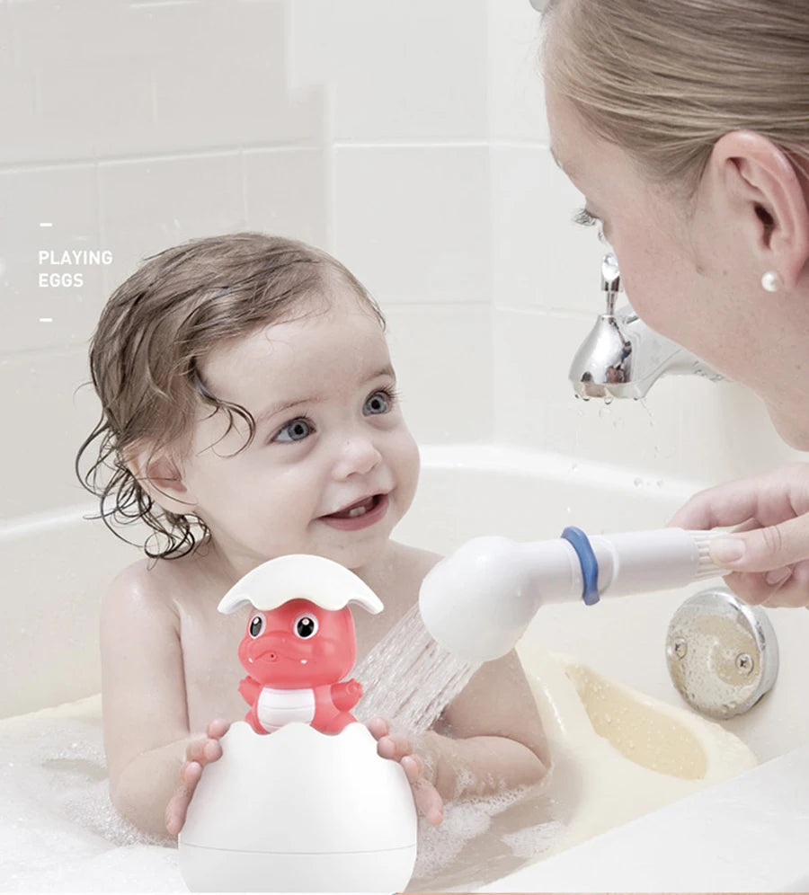 A baby is playing with a white duck and penguin bath toy that sprays water in a bathtub.