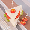 A sandwich cut into triangles with cherry tomatoes skewered on pearl bamboo sticks
