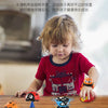 A child is playing with various spinning top race cars and toys on a wooden table.