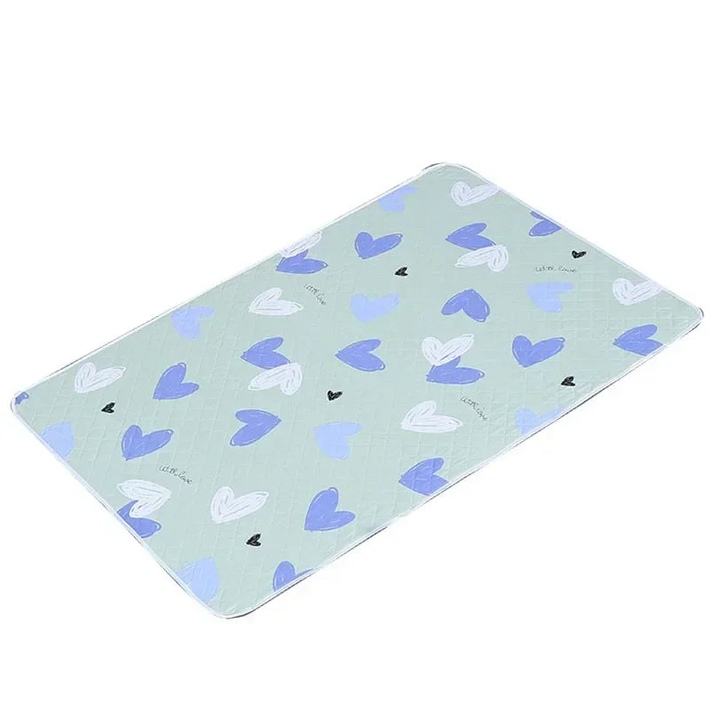 Light blue waterproof baby mattress protector featuring a pattern of small heart shapes and cute cartoon designs.