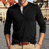 A man wearing a black long-sleeve casual shirt with a chest pocket and tan pants, standing in front of historic architecture.