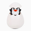 A white cartoon monkey water spray bath toy with black eyes and an orange beak emerging from a white eggshell.