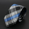 Corbata de cuadros blancos y negros con rayas azules, doblada sobre fondo oscuro.