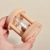 A hand holds a wooden musical instrument set for kids featuring a cartoon band kit design.