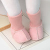 Pair of pink suede leather winter booties with soft fur lining worn on white socks.