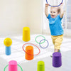 A toddler is tossing colorful rings onto stacking cups in a bright room.