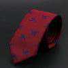 Corbata roja con patrón azul repetido de aves, enrollada sobre una superficie oscura.