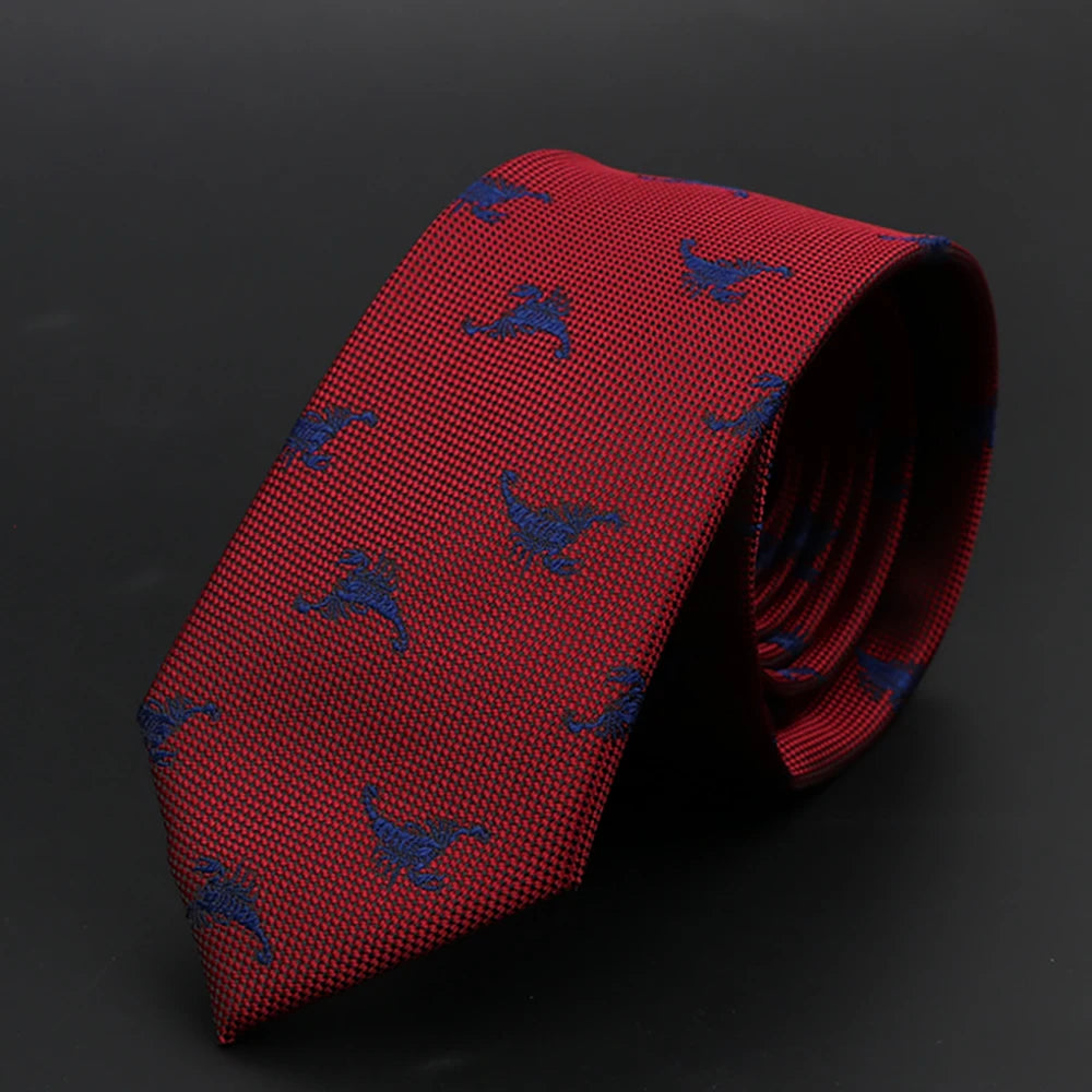 Corbata roja con patrón azul repetido de aves, enrollada sobre una superficie oscura.
