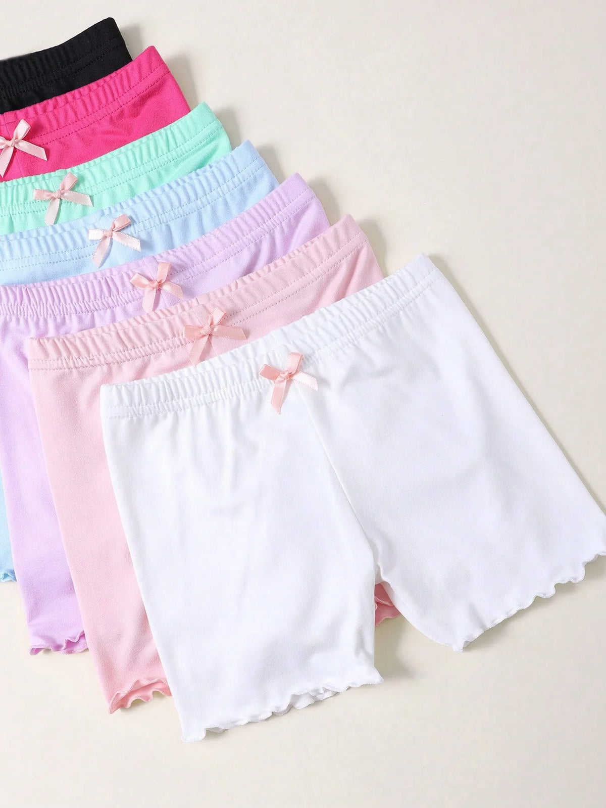 A stack of three girls bow safety shorts in various pastel colors and white, laid out for display.