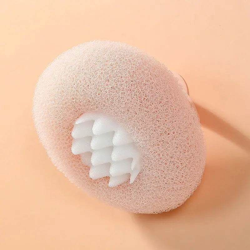 A pink bath sponge with a white, textured suction cup insert is shown on a light background.