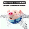 A pink plush pig toy is shown being washed under water, highlighting its removable and washable fabric.