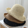 A beige crochet straw fisherman hat is stacked on a white surface.