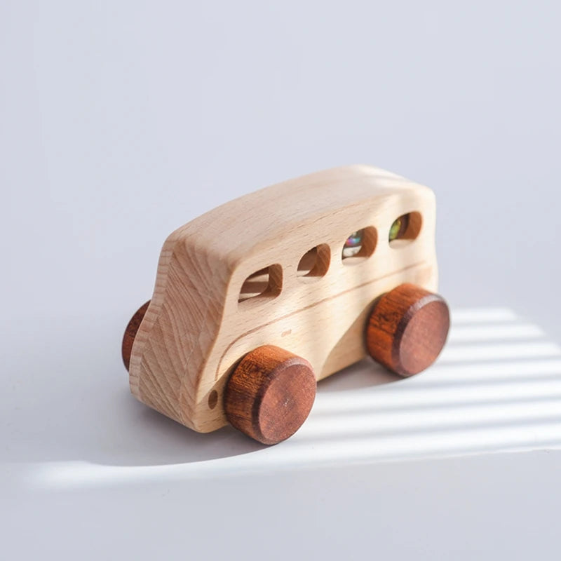 A light wooden toy cart with round wheels and small colored windows, casting a shadow on a white surface.