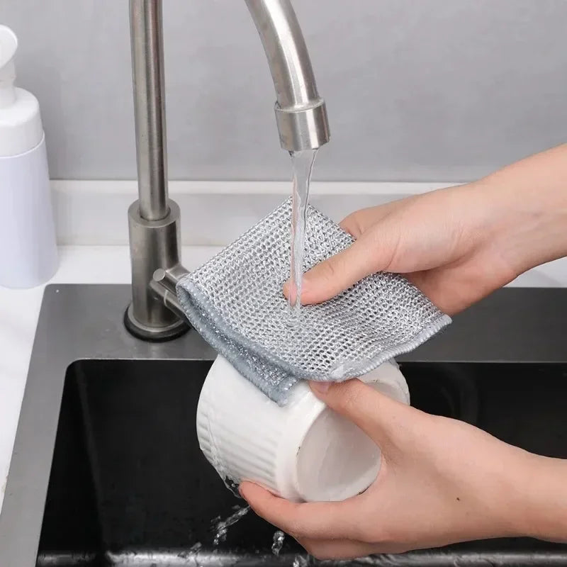 A hand is using a faucet to pour water onto a mesh microfiber cloth placed in a white container for cleaning.