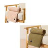 A beige portable heated shawl draped over a wooden chair, next to a light-colored cushion.