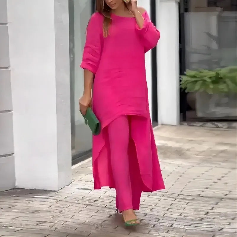 Kvinne i rosa bomull-lin loungesett med brede ben og grønn clutch.