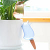 Un pic autoirrigateur en forme d'oiseau pour plantes en pot, au design en verre doré et bleu.