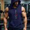 A muscular man wearing a navy blue hooded tank top and dark pants in a gym setting.