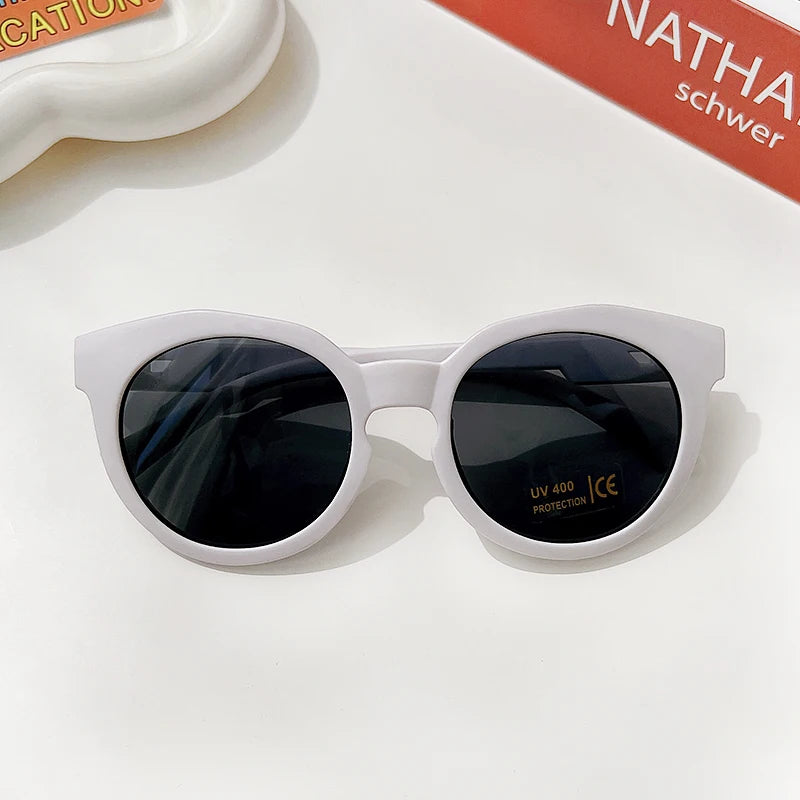 White sunglasses with dark lenses and a durable frame resting on a white surface.