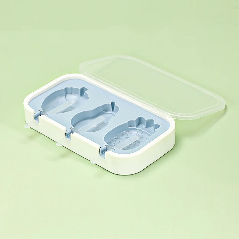 A white silicone popsicle mold tray with a clear lid and three silicone molds for making popsicles.