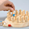 A hand is placing a wooden stick piece onto a board of small wooden figures for a Montessori memory match game.