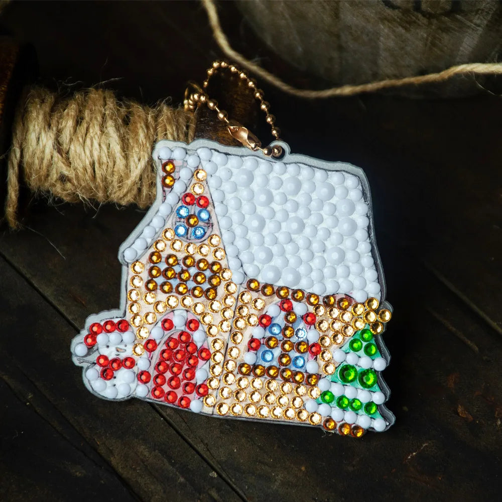 A diamond painting keychain featuring a white house design adorned with colorful rhinestones and jewels.