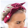 A woman wearing a deep red heatless curling rod headband tied in a knot, featuring blonde hair.