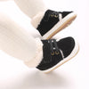 A pair of black baby winter snow boots with white fuzzy trim and light brown soles, shown on a leg.
