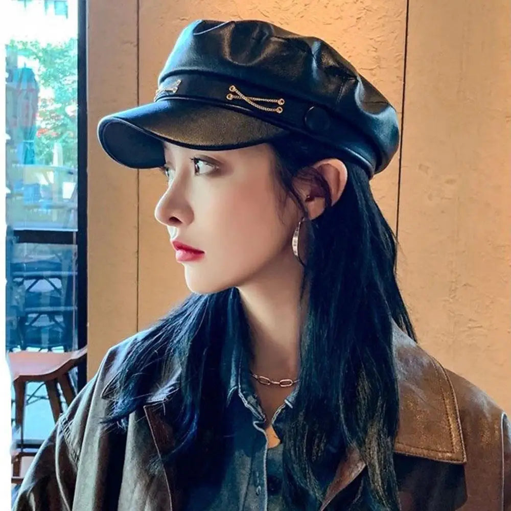 A woman wearing a black PU leather beret hat and a dark jacket looking to the side.