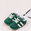 A pair of green and white baby first walker shoes with anti-slip TPR soles.