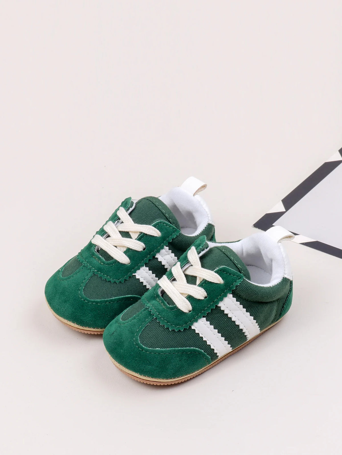 A pair of green and white baby first walker shoes with anti-slip TPR soles.