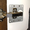 Stainless steel cabinet door hinge repair plate kit with screws mounted on a wooden surface.
