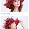 A woman models a large, ruffled red organza sun hat with mesh detailing.