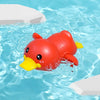 A bright red duck bath toy is floating in clear blue water surrounded by white foam blocks.
