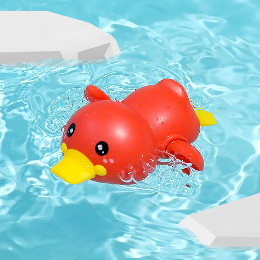 A bright red duck bath toy is floating in clear blue water surrounded by white foam blocks.