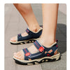 A close-up view of blue and white boys' breathable summer sport sandals with adjustable straps on a person's foot.
