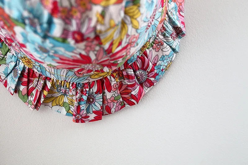 A close-up of a baby girl's floral print dress with ruffled trim and matching hat.