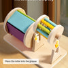 Montessori wooden spinning drum showing colorful wooden rollers placed in a groove for installation display