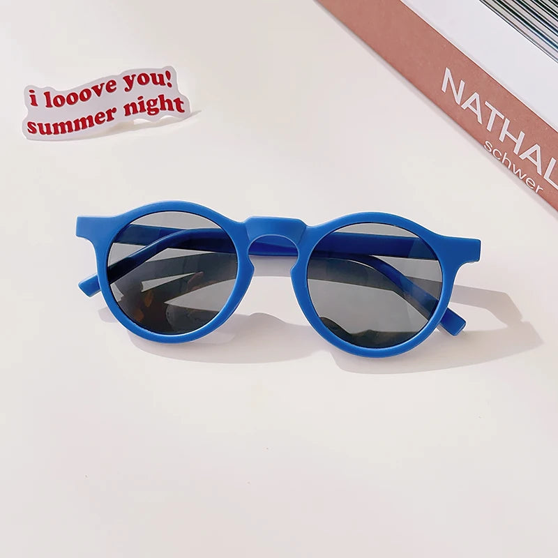 A pair of blue sunglasses with dark lenses resting on a white surface.